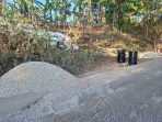 Alat berat dan tumpukan material batu koral serta aspal bersiaga di tepi jalan rusak kawasan Sengkan Selang, Tegalombo, Pacitan.