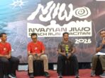 Jurnalis senior Purwoto memegang mikrofon saat berbincang dengan atlet ultra trail Rachmat Septiyanto (Mas Jon) dan jajaran panitia peluncuran Nyaman Jiwo Beach Run Pacitan 2026 di atas panggung.