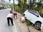 Petugas kepolisian mengevakuasi mobil Daihatsu Ayla putih bernopol AE 1498 FI yang rusak pada bumper depan usai menabrak pembatas jalan di Desa Arjosari, Pacitan.