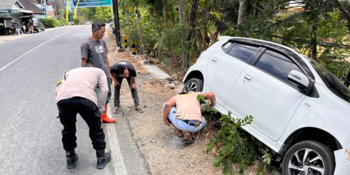Petugas kepolisian mengevakuasi mobil Daihatsu Ayla putih bernopol AE 1498 FI yang rusak pada bumper depan usai menabrak pembatas jalan di Desa Arjosari, Pacitan.