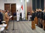 Bupati Pacitan Indrata Nur Bayuaji membacakan naskah pengukuhan di hadapan jajaran pengurus Karang Taruna Kabupaten Pacitan masa bakti 2026–2031 yang mengenakan busana adat Jawa.