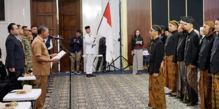 Bupati Pacitan Indrata Nur Bayuaji membacakan naskah pengukuhan di hadapan jajaran pengurus Karang Taruna Kabupaten Pacitan masa bakti 2026–2031 yang mengenakan busana adat Jawa.