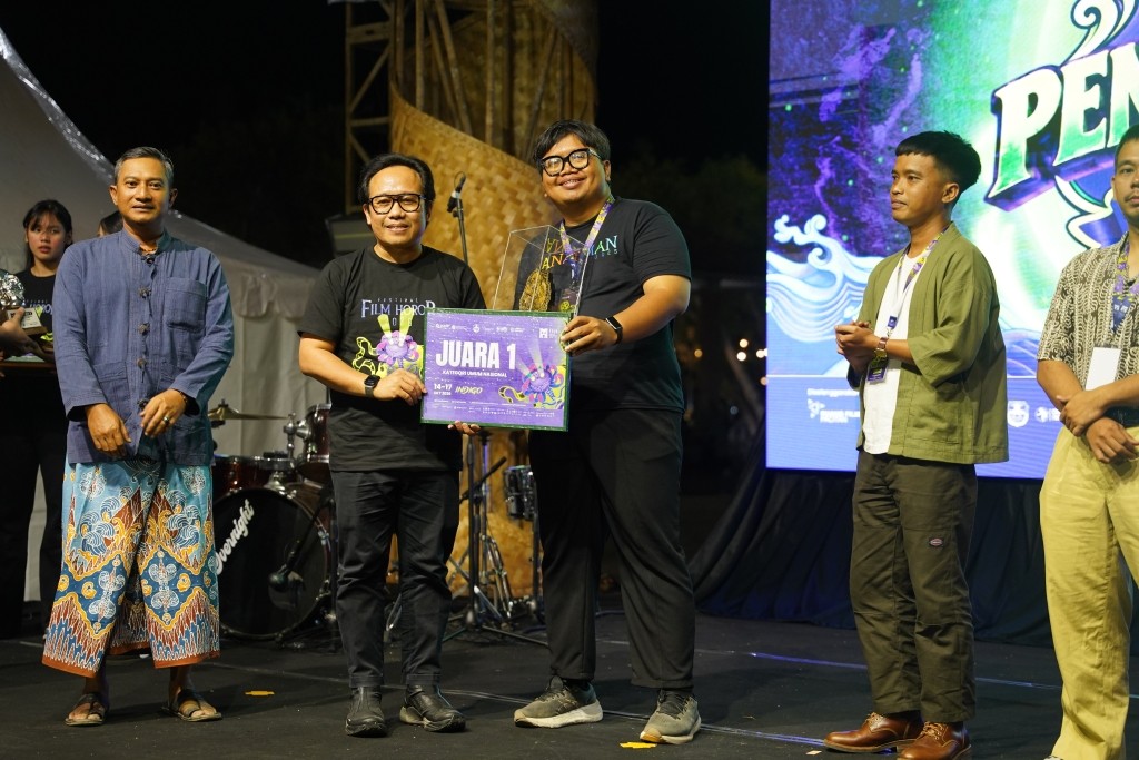 Deputi Bidang Kreativitas Media Kemenekraf Cecep Rukendi menyerahkan plakat penghargaan Juara 1 Kategori Umum Nasional kepada perwakilan pemenang film 'Hapus' pada malam puncak Festival Film Horor 2026 di Alun-Alun Pacitan.