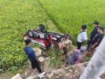 Petugas TNI bersama warga meninjau kendaraan roda tiga warna merah-putih milik Koperasi Desa Merah Putih (KDMP) yang terbalik dengan roda menghadap ke atas di area persawahan tepi JLS Pacitan.