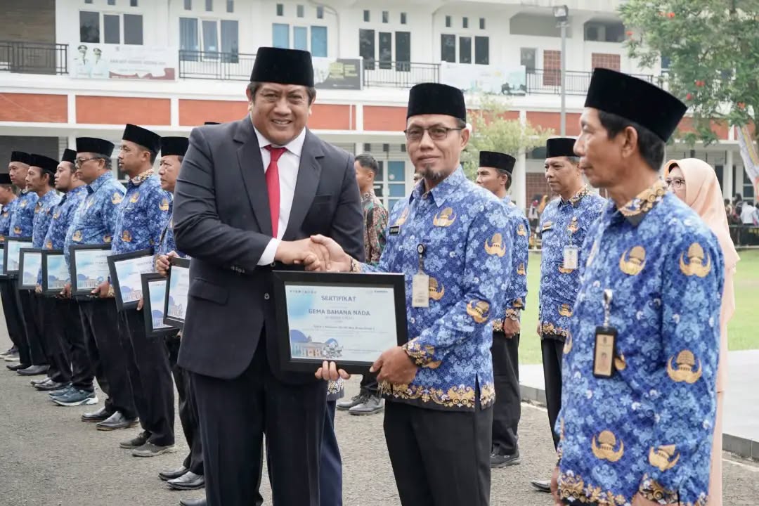 Wakil Bupati Pacitan Gagarin Sumrambah berjabat tangan dan menyerahkan sertifikat penghargaan Gema Bahana Nada kepada perwakilan ASN berseragam Korpri pada upacara Hari Sumpah Pemuda ke-98 di halaman Pendopo Kabupaten Pacitan.